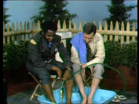 Officer Clemmons and Mr. Rogers share a hose in a pool